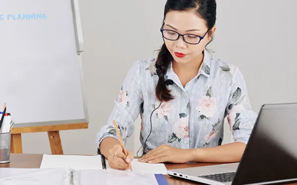 teacher sitting at a desk writing